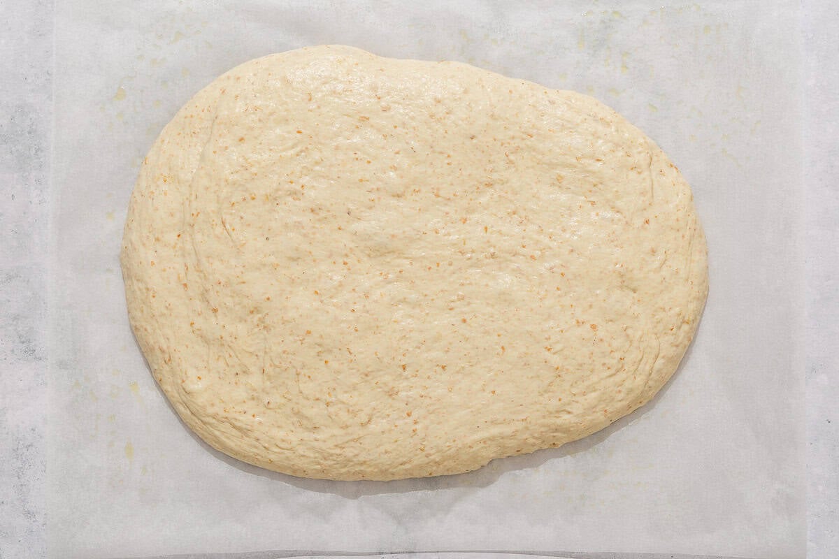 The dough for the fougasse shaped on a piece of parchment paper.