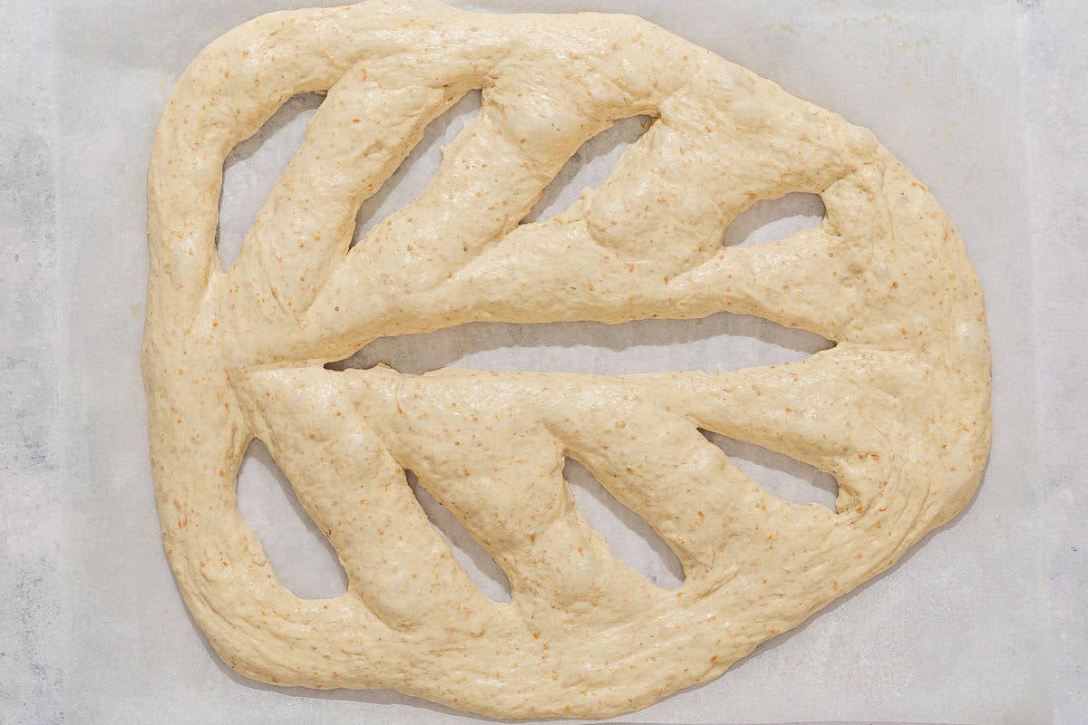 An overhead photo of unbaked fougasse on a sheet of parchment paper.