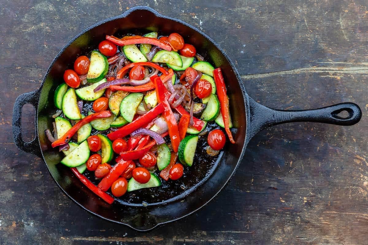Cooked vegetables for the pesto chicken recipe in a cast iron skillet.