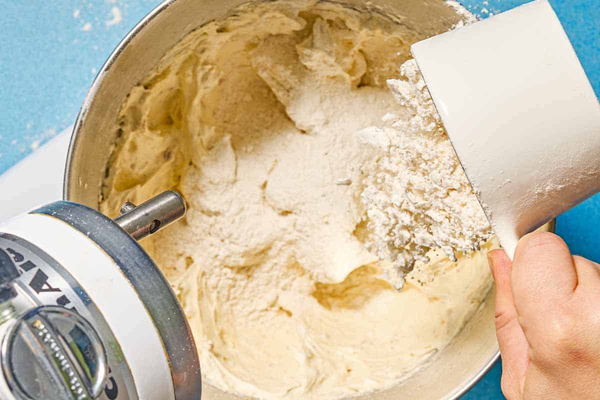 Flour being added to the other ingredients for the almond cookies in the bowl of a stand mixer.