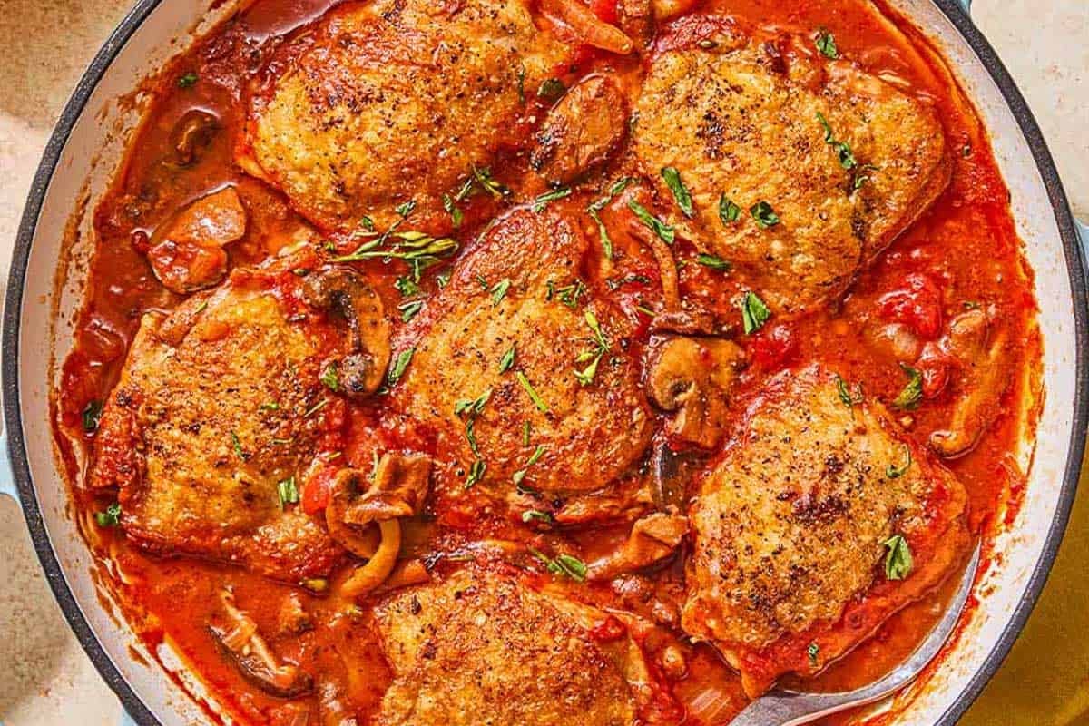 An overhead photo of chicken chasseur in a skillet.