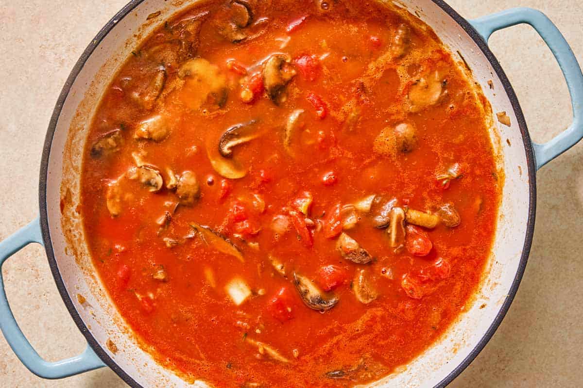 The vegetables for the chicken chasseur simmering in the tomato sauce in a skillet.