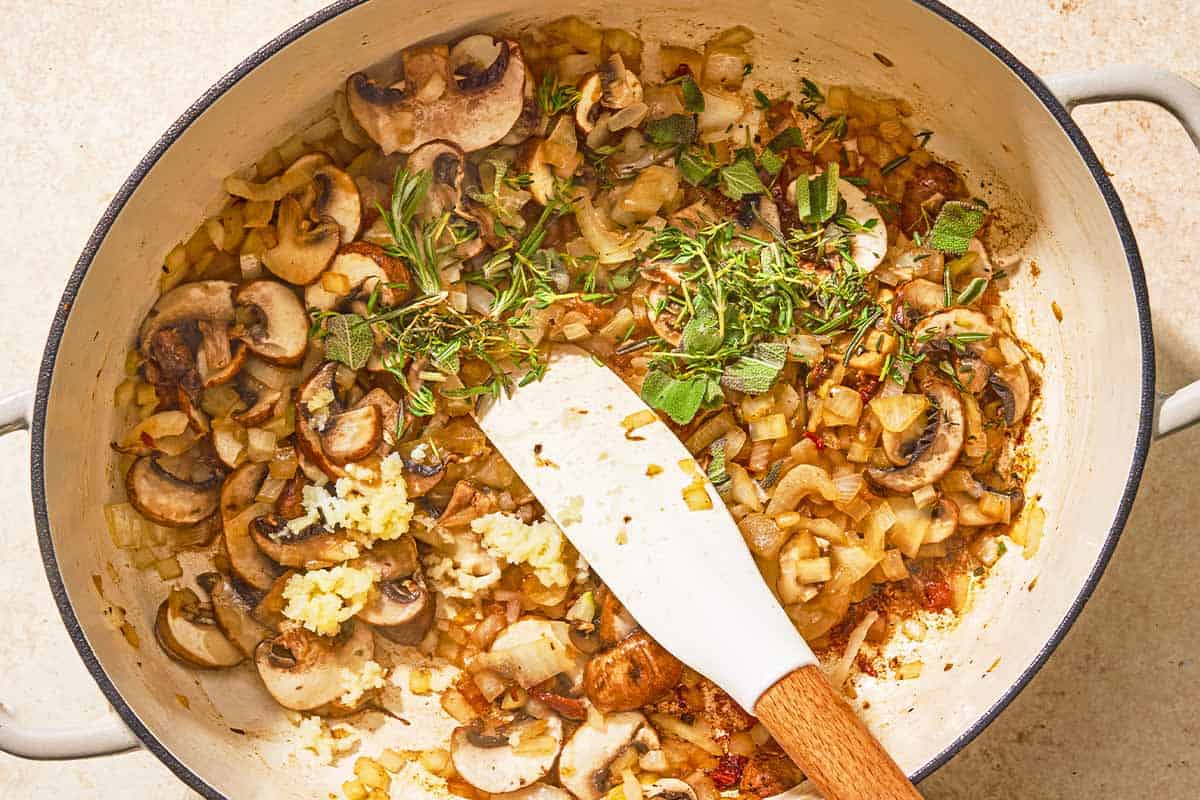 The sautéed vegetables and herbs for the chicken risotto being stirred in a large pot.