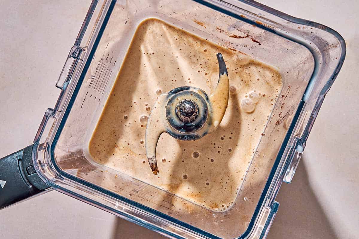 The ingredients for the vegan eggnog in the pitcher of a blender after being mixed together.