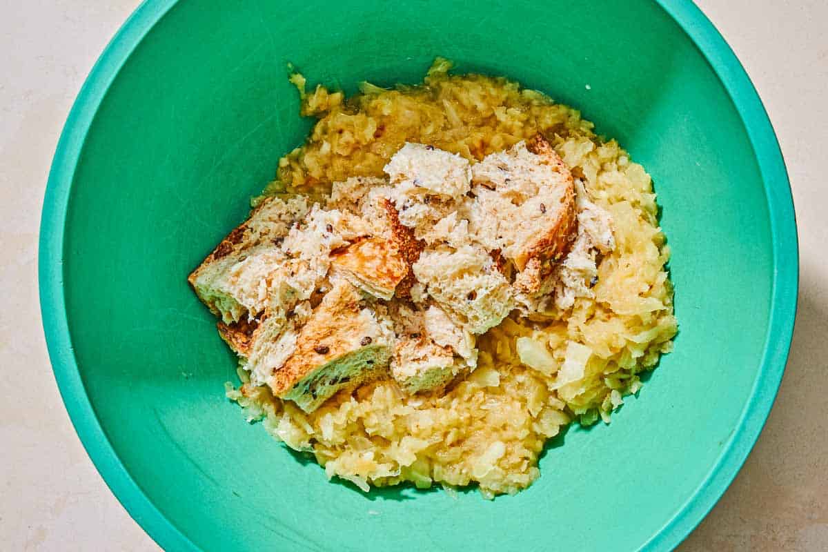 The soaked bread pieces and sauteed onions and garlic for the keftedes in a bowl.