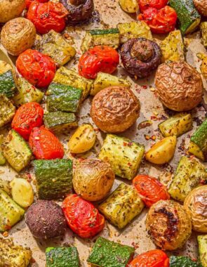 The roasted vegetables recipe on a sheet pan with serving utensils.