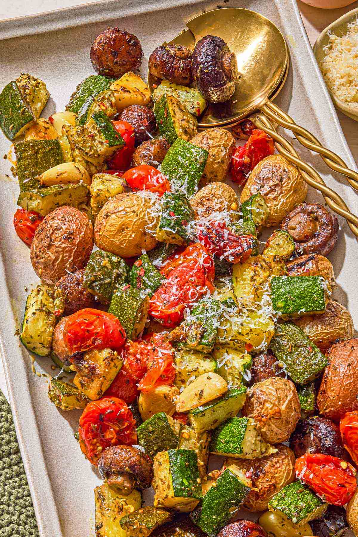 The roasted vegetables recipe on a platter with serving utensils.