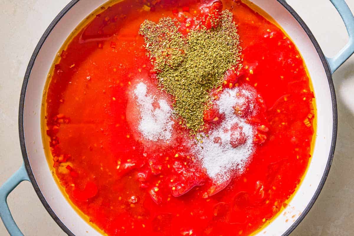 The tomato sauce along with the seasonings for the marinara sauce simmering in a skillet.