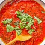 Marinara sauce in a skillet with a wooden spoon just after the fresh basil was added.