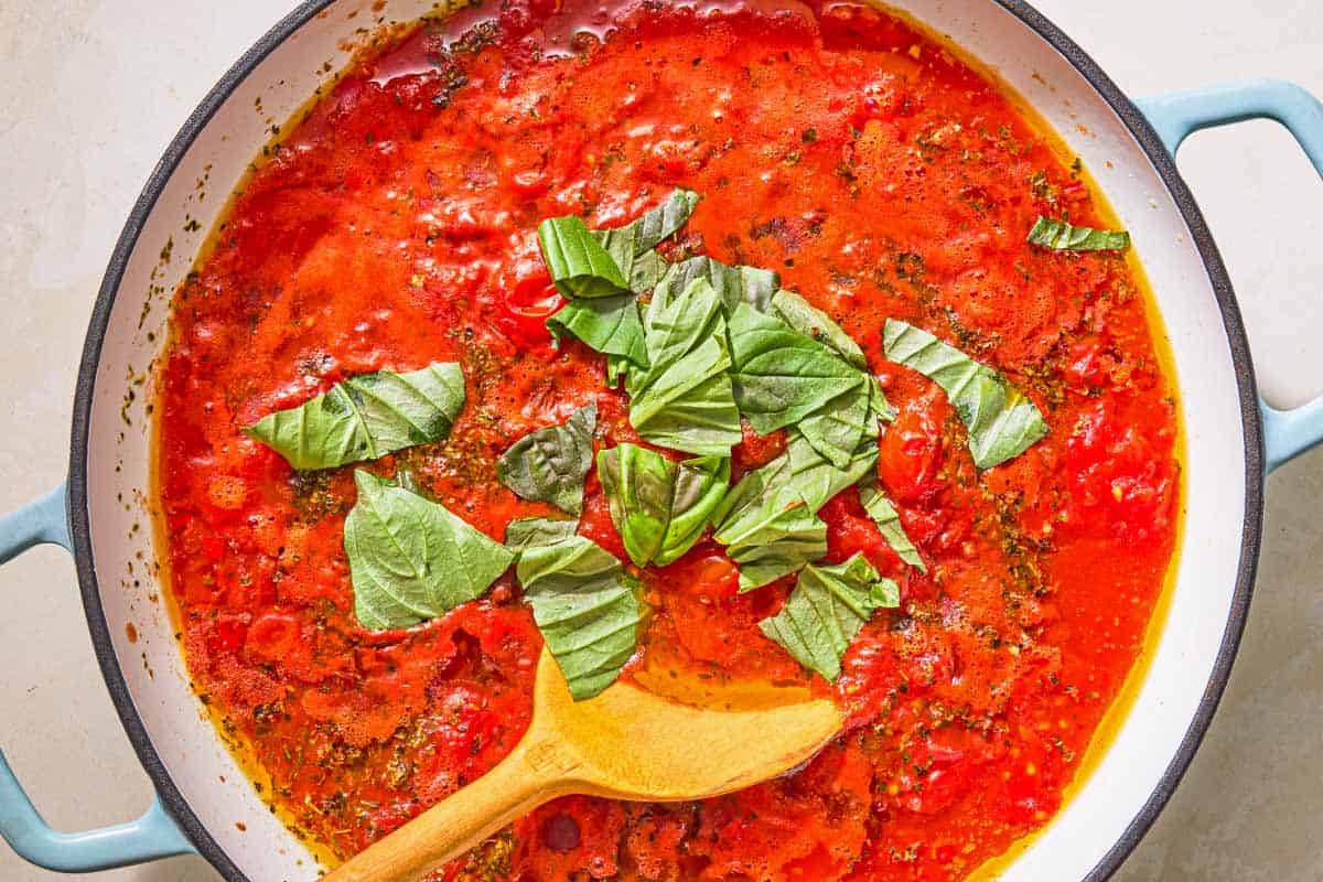 Marinara sauce in a skillet with a wooden spoon just after the fresh basil was added.