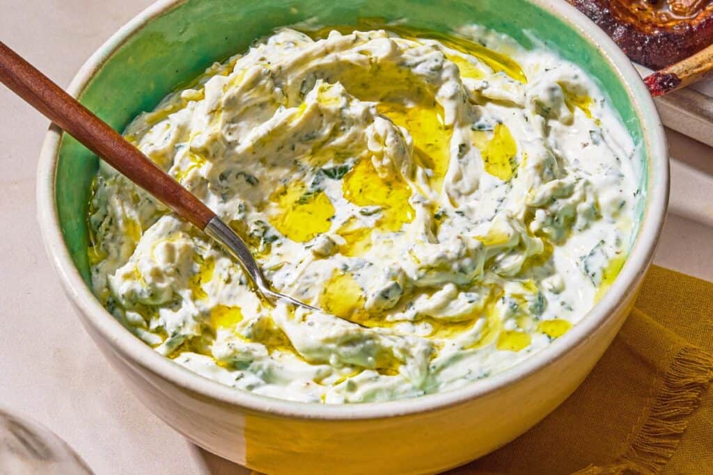 Mint yogurt sauce in a bowl with a spoon.
