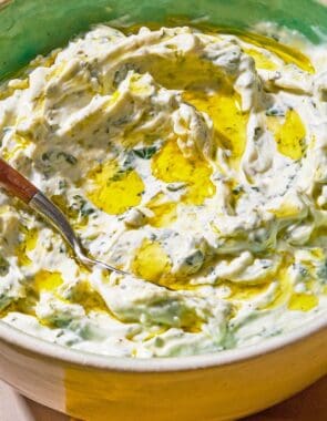 Mint yogurt sauce in a bowl with a spoon.