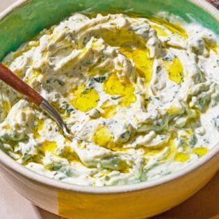 Mint yogurt sauce in a bowl with a spoon.