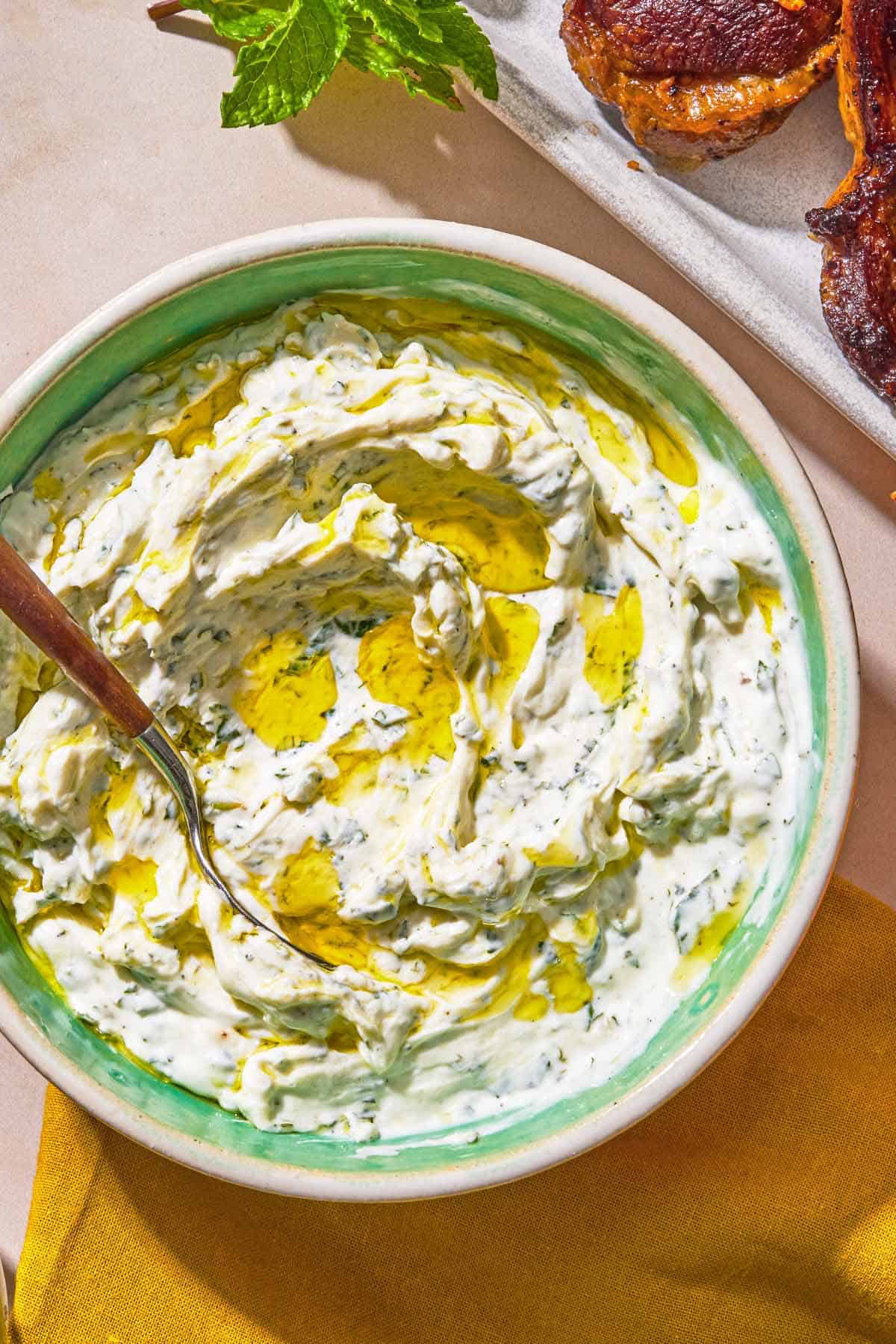 Mint yogurt sauce in a bowl with a spoon.