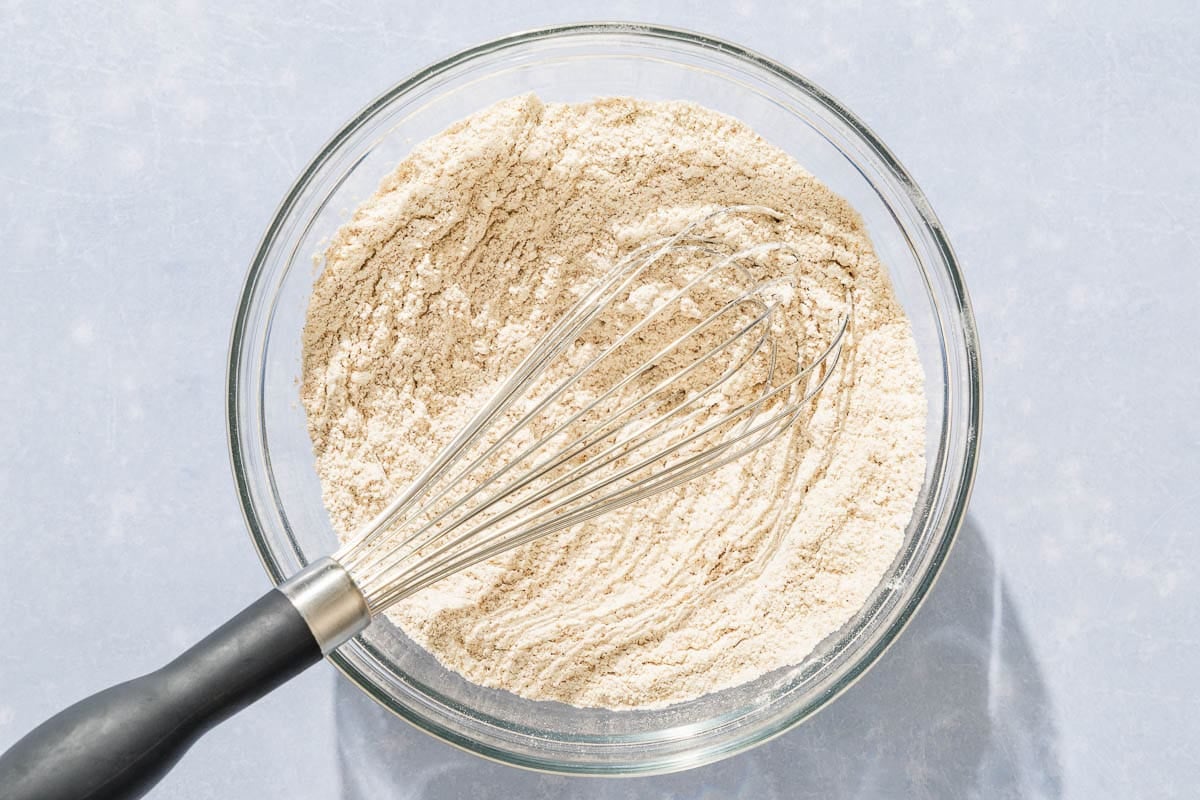 The dry ingredients for the dat nut bread recipe in a bowl with a whisk.