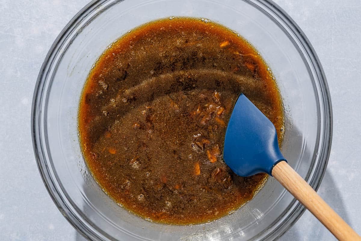 The wet ingredients for the date nut bread recipe in a bowl with a spatula.