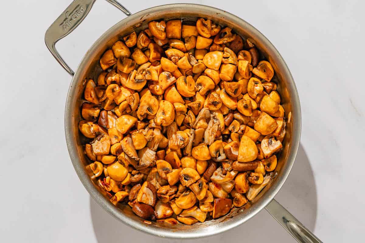 The mushrooms for the mushroom stew being sauteed in a tall sided skillet.