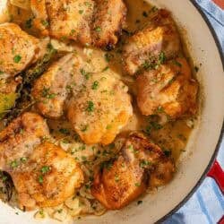 The garlic chicken recipe in a skillet next to a bowl of chopped parsley.