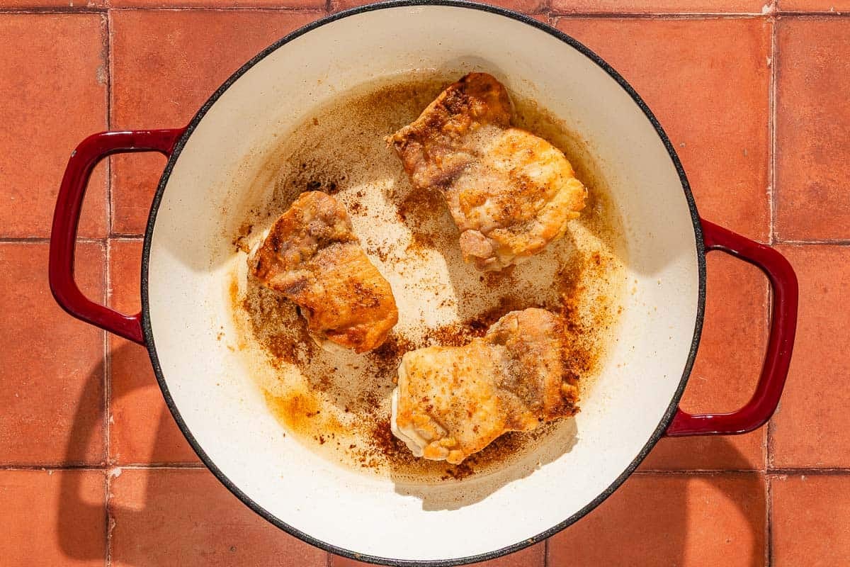 The chicken thighs for the garlic chicken recipe being seared in a skillet.