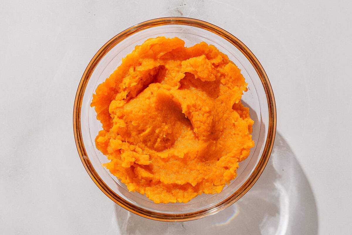 The steamed, mashed sweet potato in a bowl.