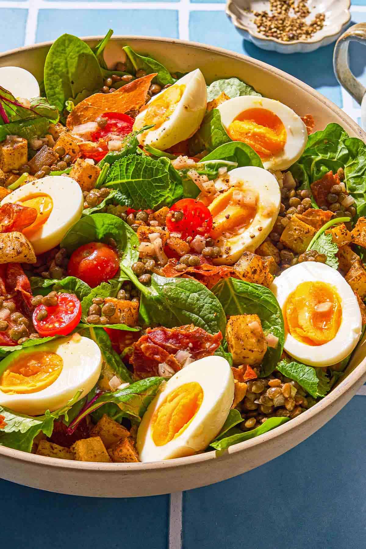 The breakfast salad in a serving bowl next to a small bowl of dried oregano.
