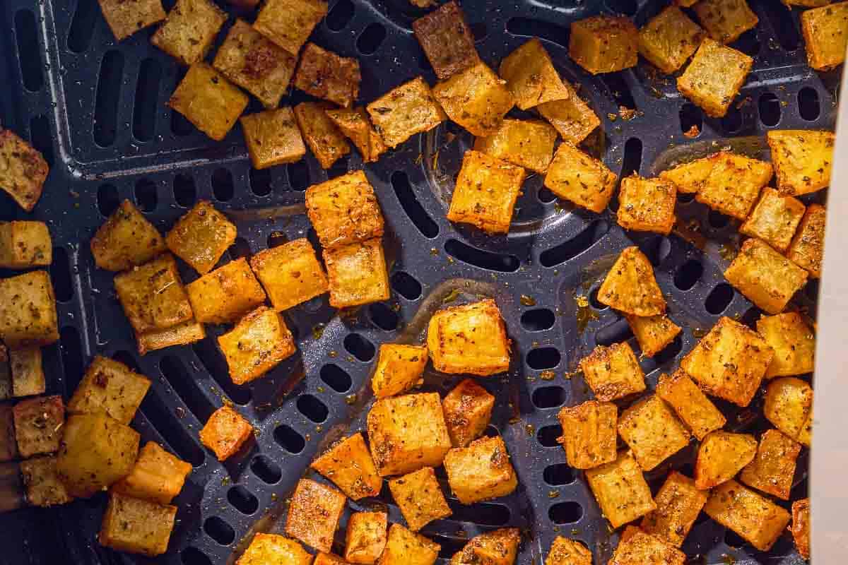 The potato croutons for the breakfast salad in the basket of an air fryer.