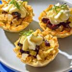 Three phyllo cups with a plate on a stack of napkins.