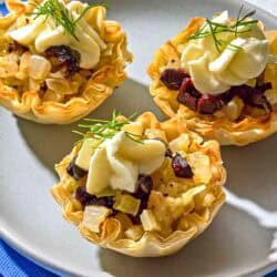 Three phyllo cups with a plate on a stack of napkins.