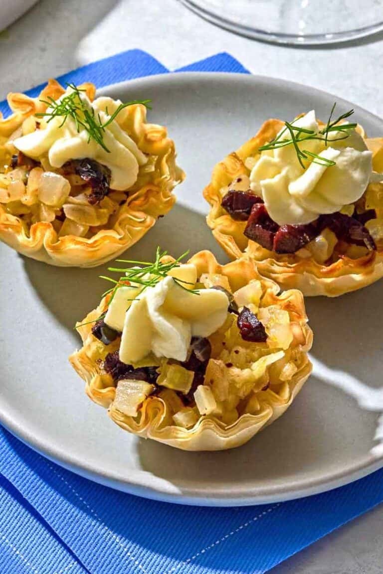 Three phyllo cups with a plate on a stack of napkins.