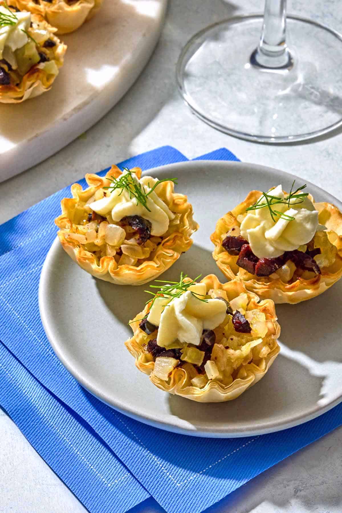Three phyllo cups with a plate on a stack of napkins.