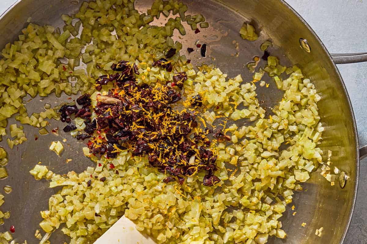 The chopped fennel, garlic, shallot, chopped olives and orange zest for the phyllo cups being sauteed in a skillet.