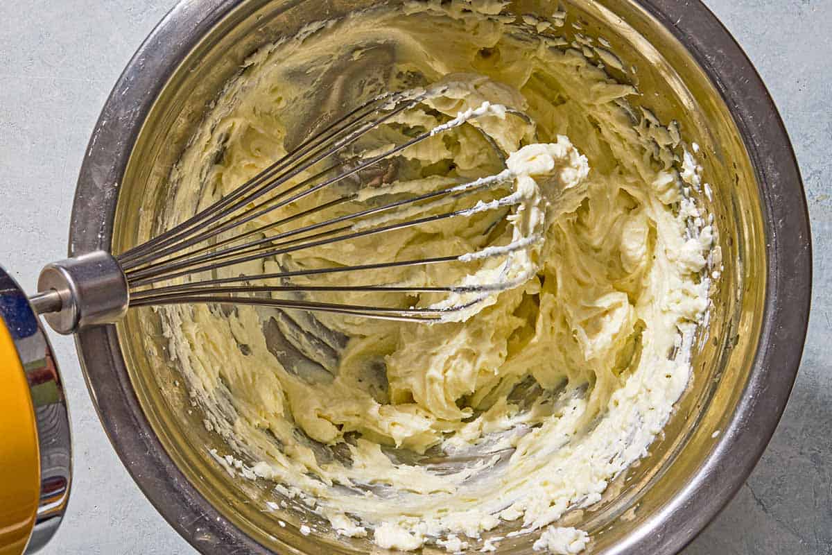 The goat cheese for the phyllo cup appetizers being whipped with the honey and orange juice in a bowl with a whisk.