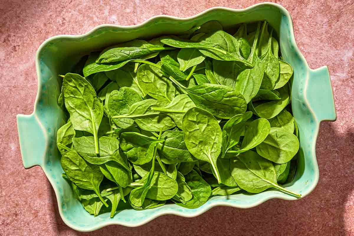 Baby spinach spread evenly in a baking dish.