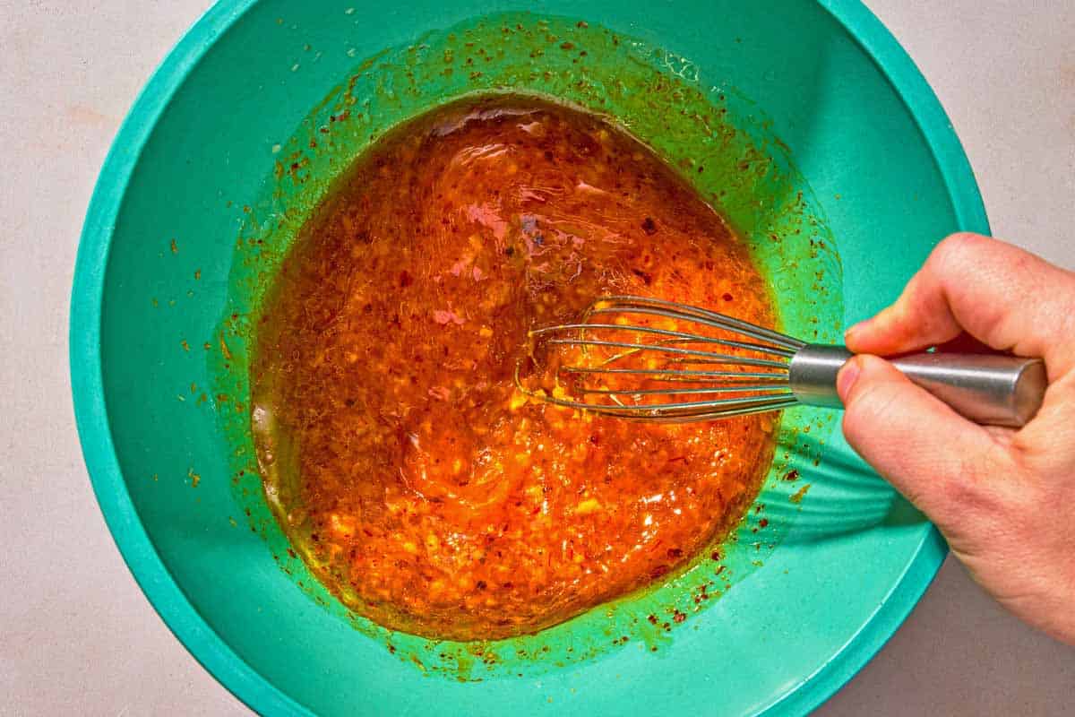 The saffron marinade for the lamb lollipops being stirred in a bowl with a whisk.