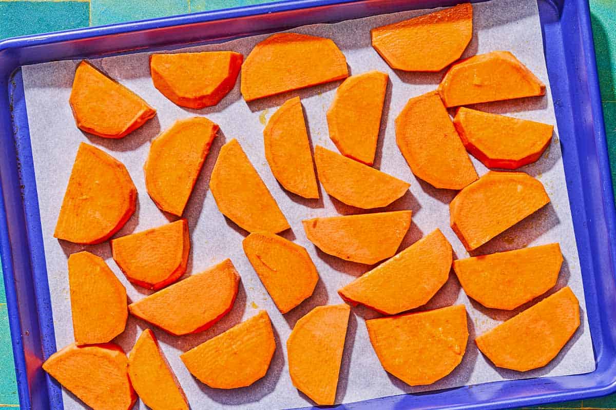 Slices of sweet potato on a parchment lined sheet pan.