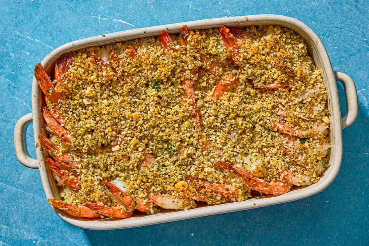 Shrimp oreganata with lemon wedges in a baking dish.