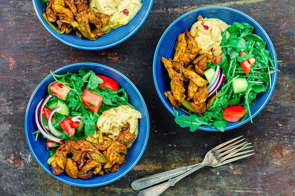 3 chicken shawarma bowls next to 2 spoons.