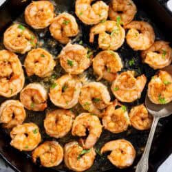 Honey garlic shrimp in a cast iron skillet with a spoon.