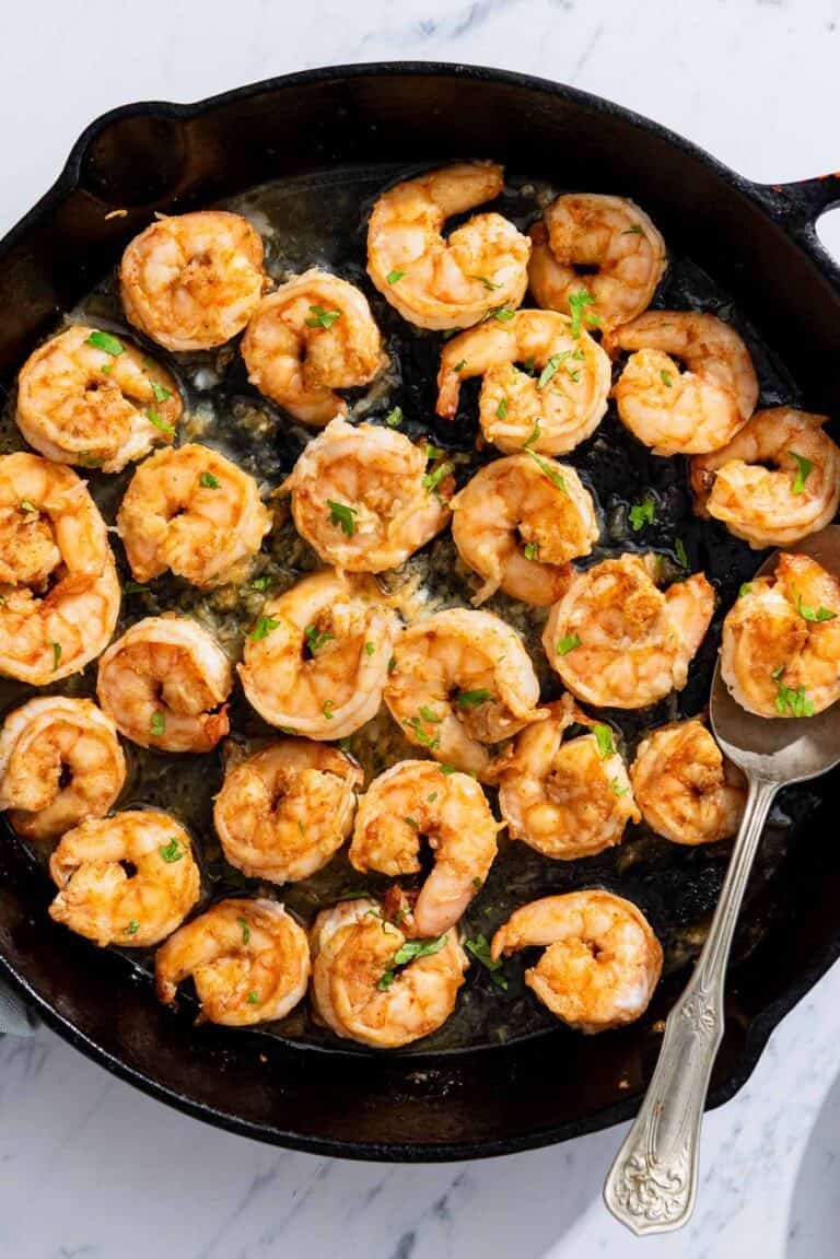 Honey garlic shrimp in a cast iron skillet with a spoon.