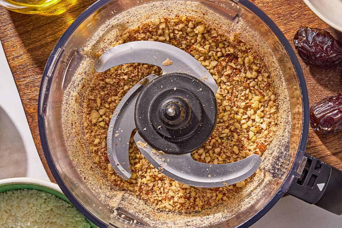 The almonds in the bowl of a food processor after being blitzed.