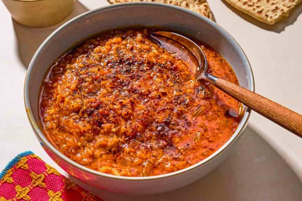 Turkish lentil stew topped with infused olive oil in a bowl with a spoon.