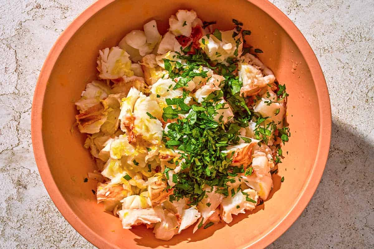 The lobster meat, lemon zest and parsley for the lobster pasta in a bowl.