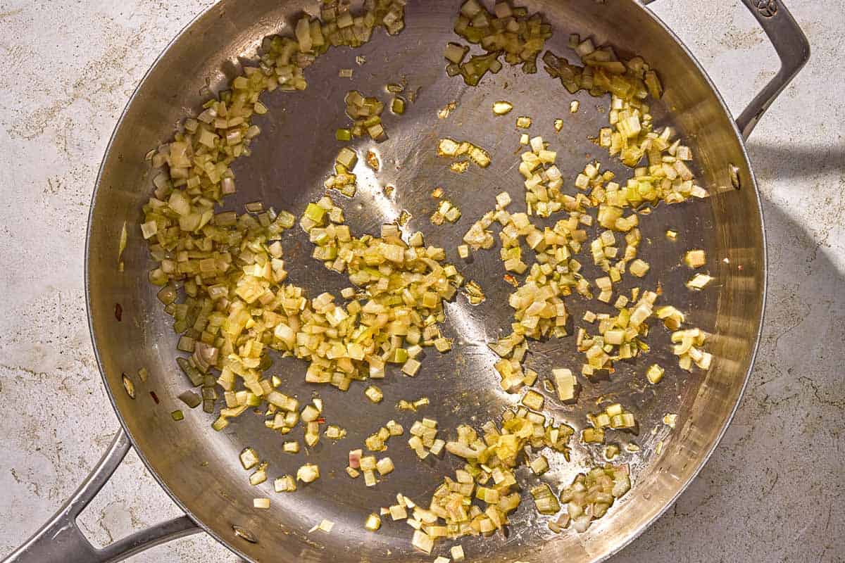 The chopped shallots for the lobster pasta being sautéed in a skillet.