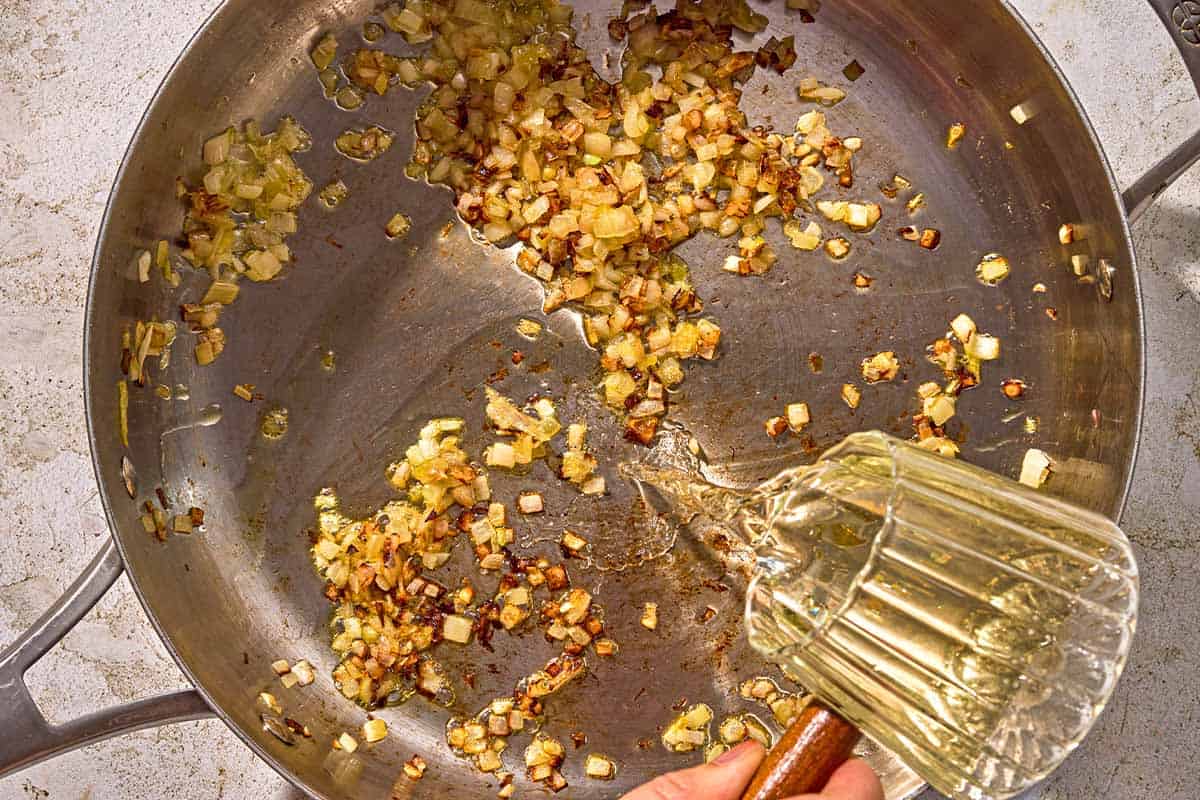 The skillet for the lobster pasta being deglazed with white wine.