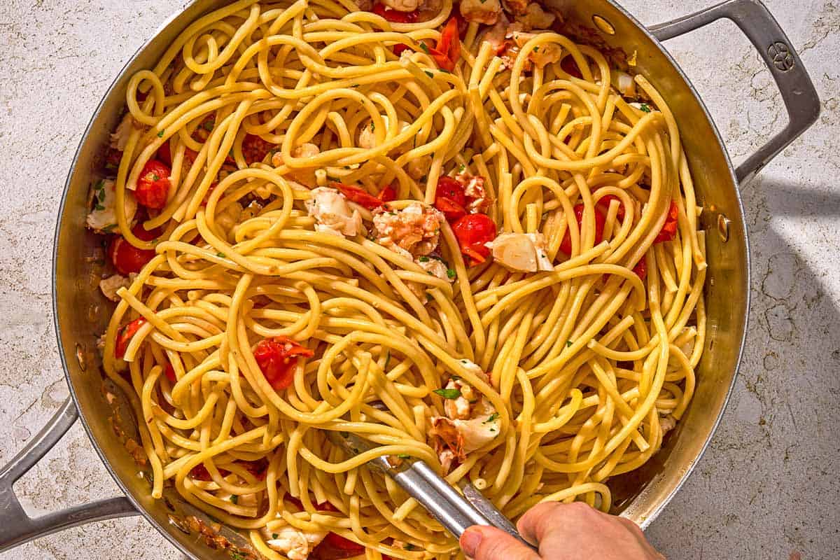 The lobster pasta being stirred in a skillet just after the pasta was added.