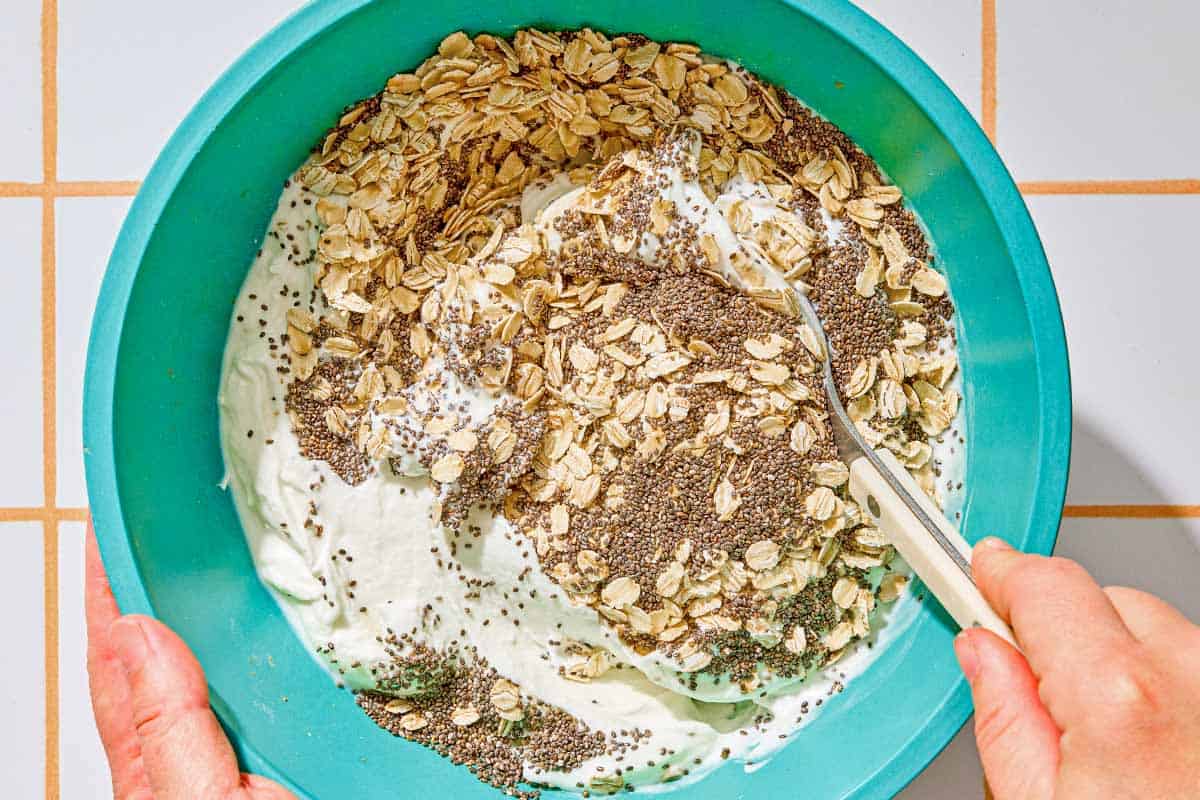 The overnight oats being mixed together in a bowl with a spoon.