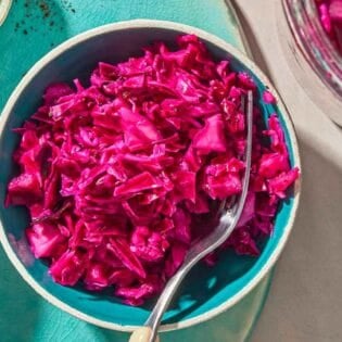 A bowl of pickled cabbage with a fork.
