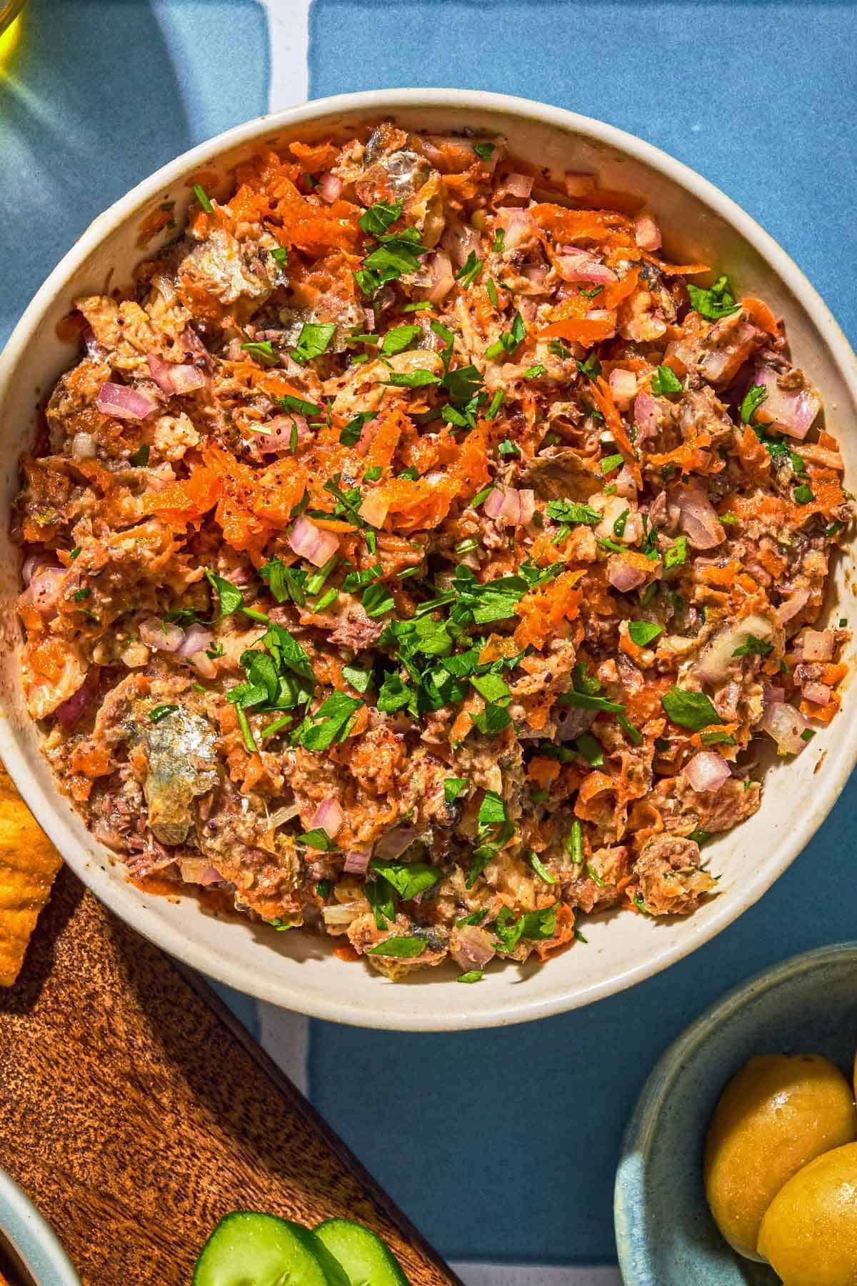 Sardine dip in a bowl next to a bowl of olives.