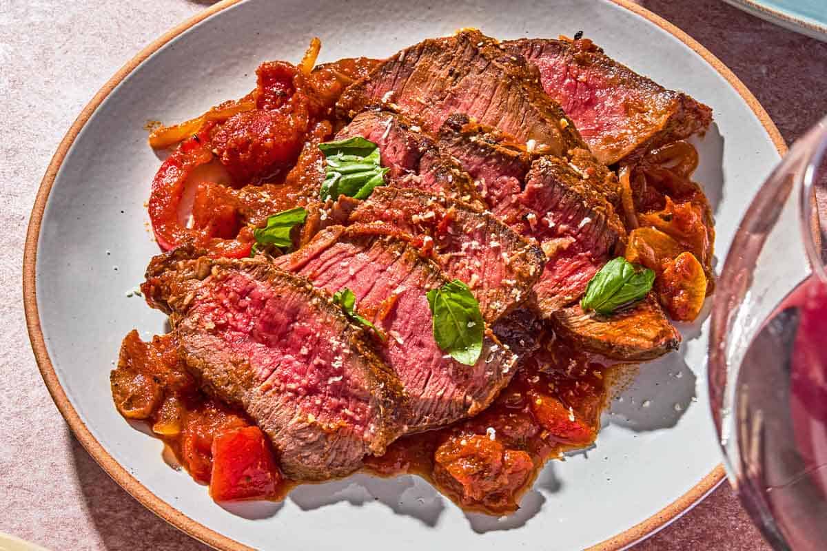 A serving of steak pizzaiola on a plate.