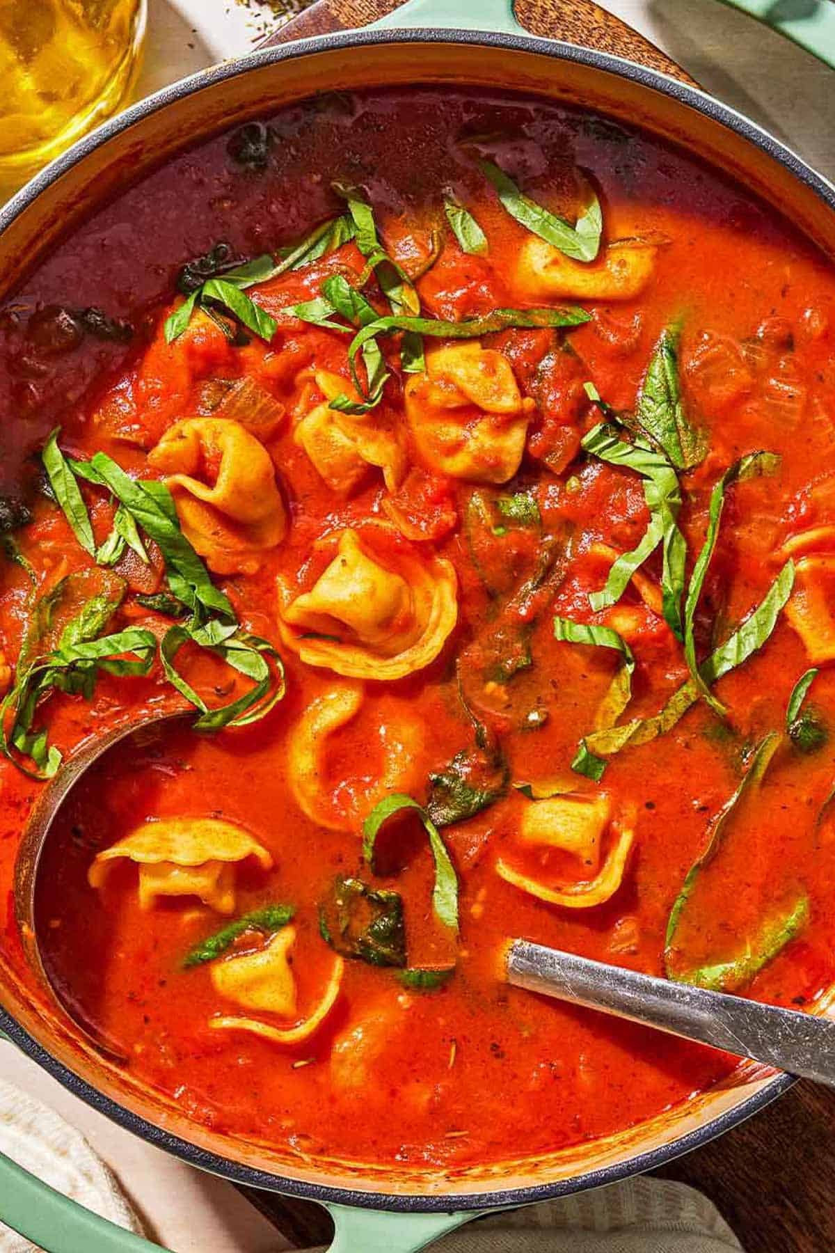 Tomato tortellini soup in a pot with a ladle.